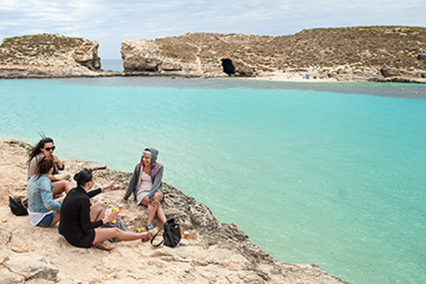Luther students sit by the ocean while studying in Malta.
